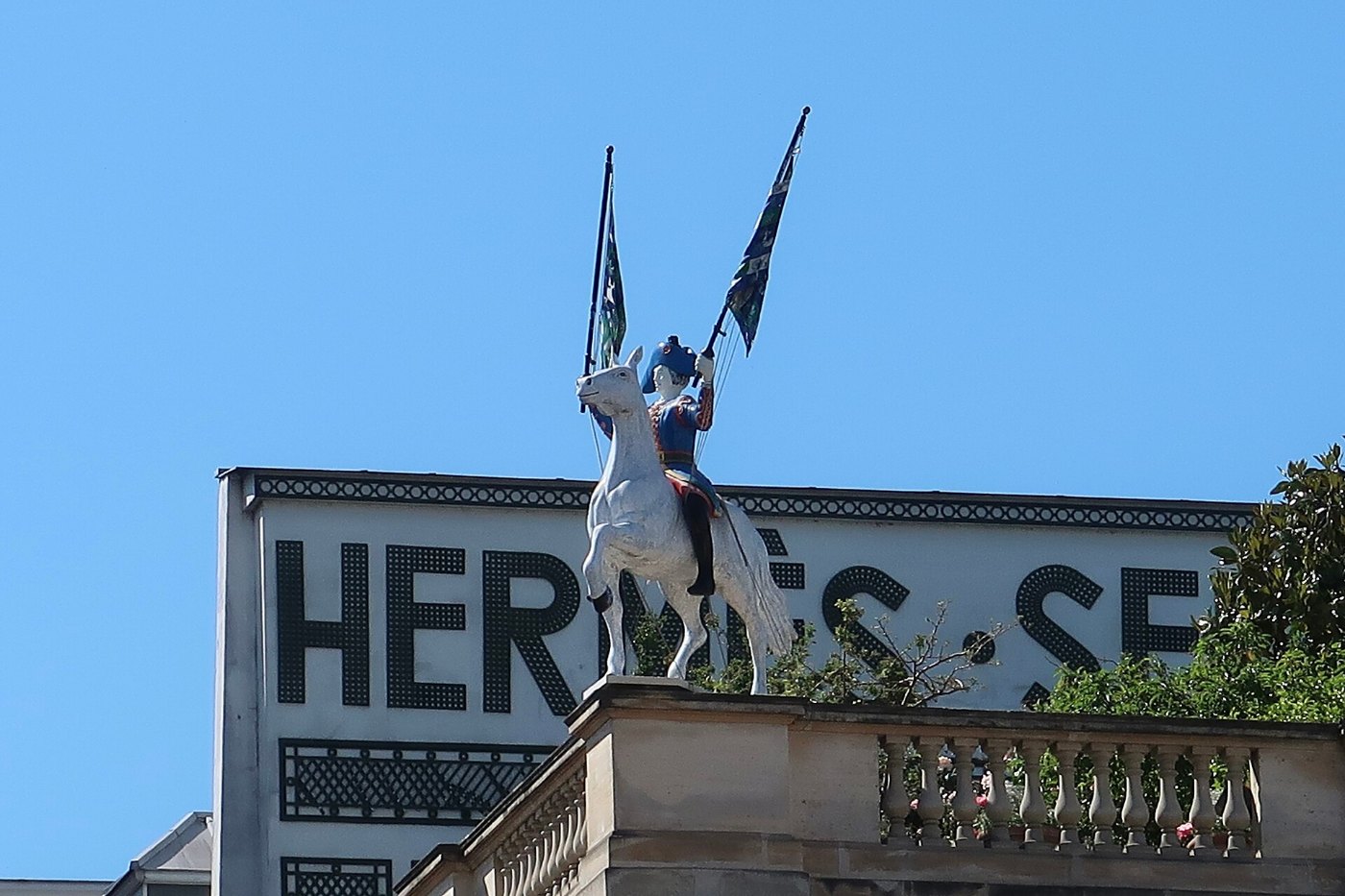 El jinete con banderas sobre el techo de la casa madre de Hermès, en el 24 del Faubourg Saint-Honoré, con las letras Hermès Sellier en la fachada.